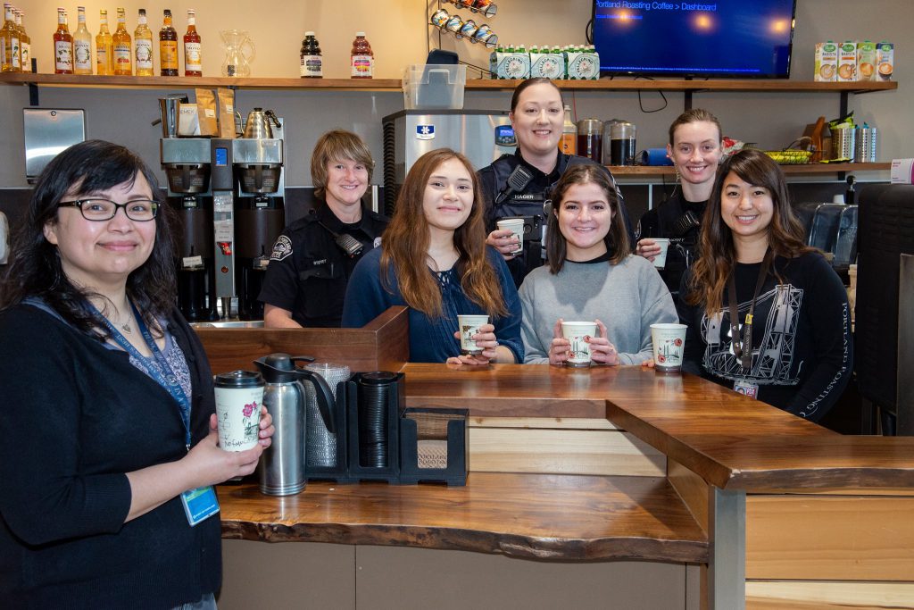 Portland Coffee Roasters employees hold coffee and smile