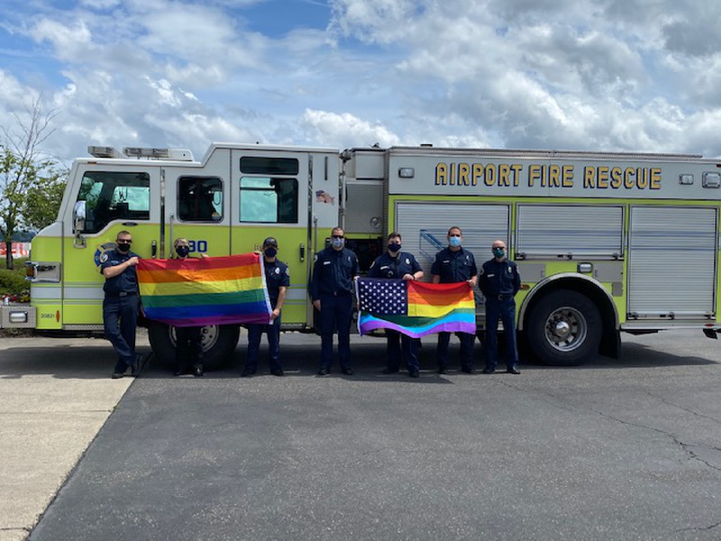 Lani Hill and other Portland Airport Firefighters stand in front of fire truck with Pride flags