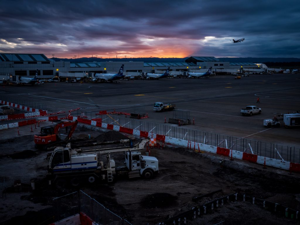 The sun sets in the background behind construction work at PDX