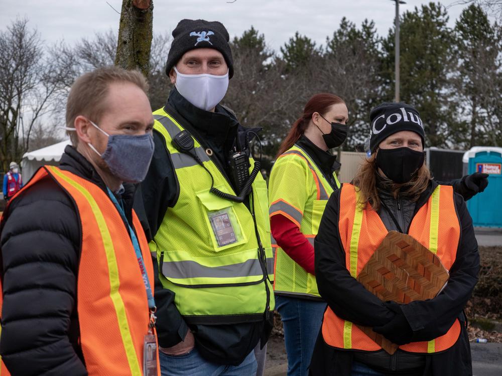The Port of Portland's Steve Koester, Michael Huggins, and Kama Simonds are bundled up and with safety vests on while they wark at the vaccine clinic's first day of operations. 