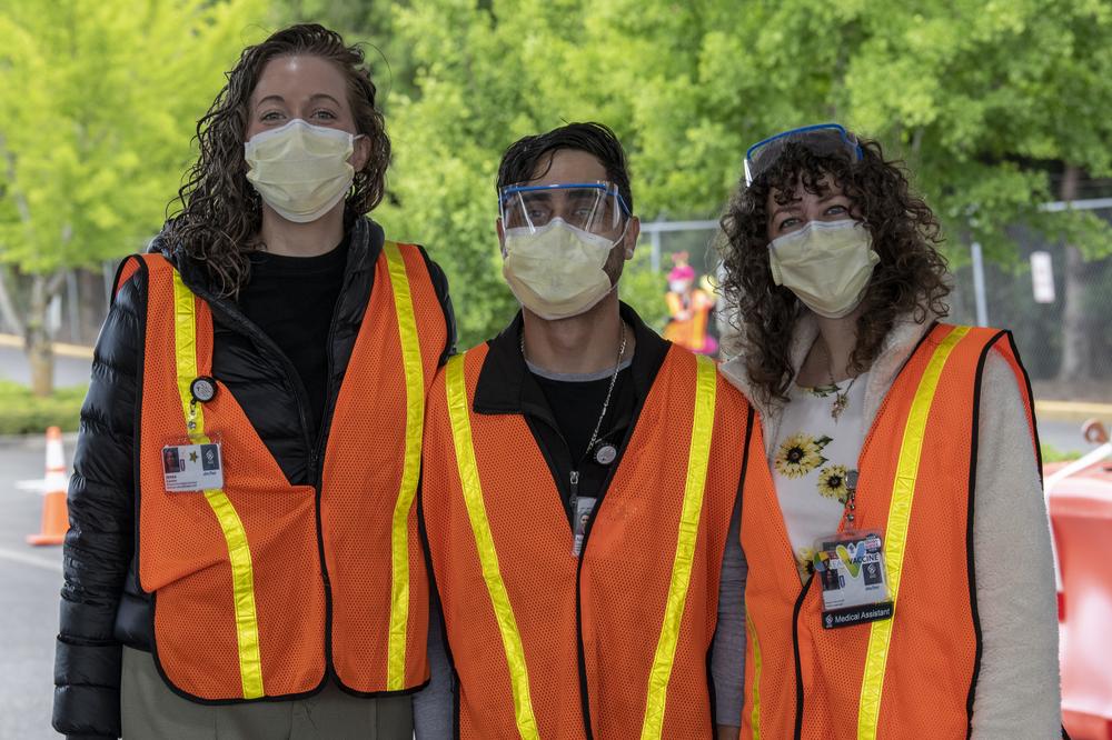 One man and two women post for a photo wearing safety goggles and masks. They are providing vaccines at the PDX Red Lot
