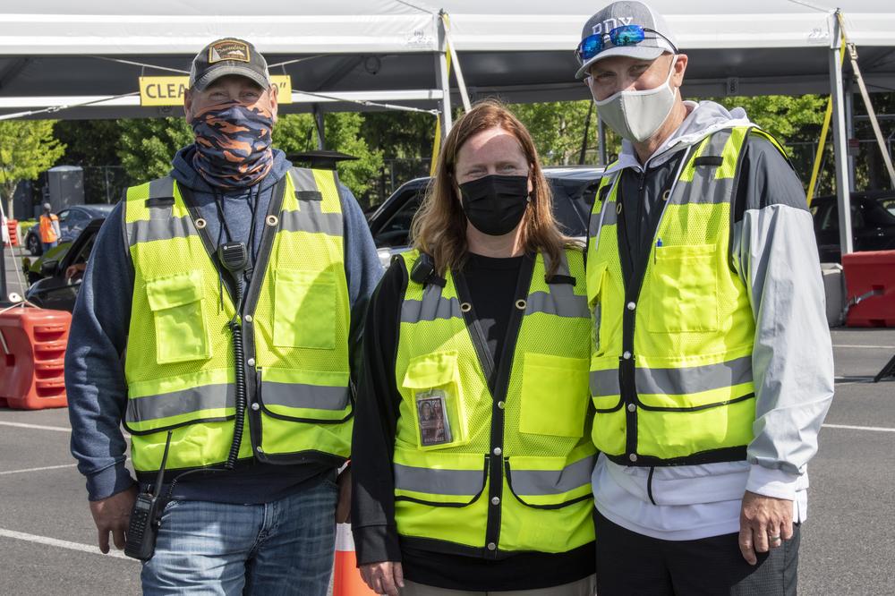 Two men and a woman from the Port of Portland post with yellow safety vests one